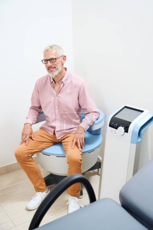 Téléchargez les photos : Vieil homme barbu subissant une physiothérapie dans un établissement médical moderne, la clinique dispose d'un équipement efficace - en image libre de droit