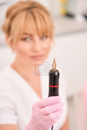 Photo for Device for permanent makeup in the hands of a master, a woman wearing protective gloves - Royalty Free Image