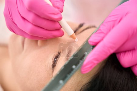 Photo for Specialist marks the clients eyebrows before the procedure, the master uses a special pencil and ruler - Royalty Free Image