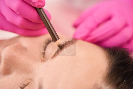 Foto de Marcando las cejas de los clientes antes del procedimiento, el maestro trabaja en guantes rosados - Imagen libre de derechos
