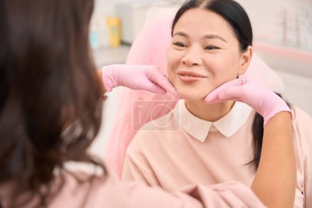 Photo for Esthetician doctor analyzes the patients skin turgor, a woman works in protective gloves - Royalty Free Image