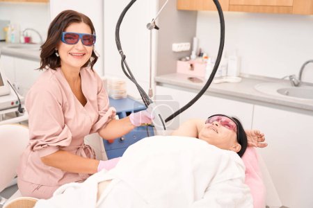 Photo for Beauty master performs laser hair removal procedure, women wearing safety glasses - Royalty Free Image