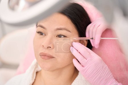 Téléchargez les photos : Femme asiatique recevant des injections de beauté dans une clinique de cosmétologie, spécialiste travaillant dans des gants de protection - en image libre de droit