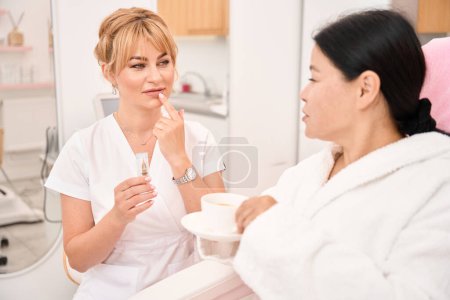 Photo for Tattoo artist talks over a cup of coffee with a client, the professional has a special device - Royalty Free Image