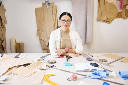 Foto de Mujer diseñadora en un taller en su lugar de trabajo, recortando tela azul en una mesa de corte - Imagen libre de derechos