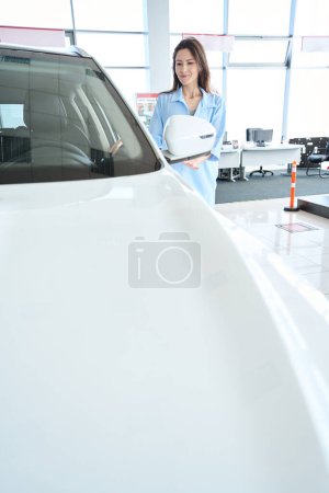 Téléchargez les photos : Jeune femme attrayante dans des vêtements élégants en choisissant une nouvelle voiture dans le showroom de voiture - en image libre de droit