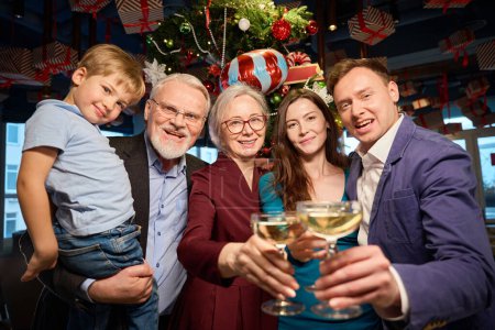 Téléchargez les photos : Bonne famille célébrant le Nouvel An nuit étant d'humeur festive tenant verres de champagne profiter du restaurant fête de vacances - en image libre de droit