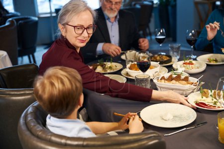 Téléchargez les photos : Famille assise à une table festive dans le restaurant tout en célébrant Noël - en image libre de droit