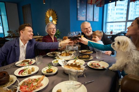 Téléchargez les photos : Femmes gaies hommes petit garçon réjouissant vacances d'hiver célébrant le Nouvel An avec du vin au restaurant - en image libre de droit
