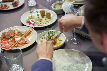 Foto de Hombre irreconocible comiendo deliciosos platos en el restaurante disfrutando de una sabrosa comida mientras cenamos - Imagen libre de derechos
