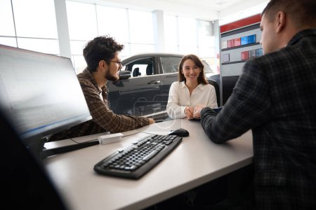 Photo for Happy beautiful couple buying new car at dealership talking with manager about leasing - Royalty Free Image