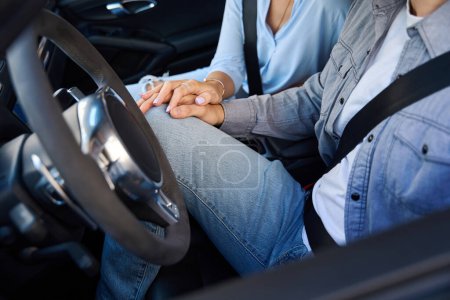 Photo for Cropped image of man and woman holding hands of each other in automobile. Concept of romantic relationship. Idea of road trip,travelling and vacation - Royalty Free Image
