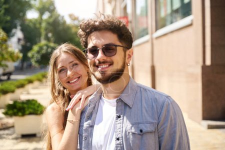 Téléchargez les photos : Récolté jeune couple souriant européen regardant la caméra en ville lors d'une chaude journée d'été. Concept de relation amoureuse et date - en image libre de droit