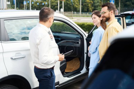 Photo for Buyers inspect the interior of a new car, they are advised by a customer relations manager - Royalty Free Image