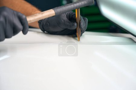 Photo for Process of using a straightening stick to level out body dents, a person works wearing protective gloves - Royalty Free Image