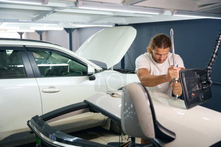 Photo for Male uses a special tool to level out body dents, a man straightens a white car - Royalty Free Image