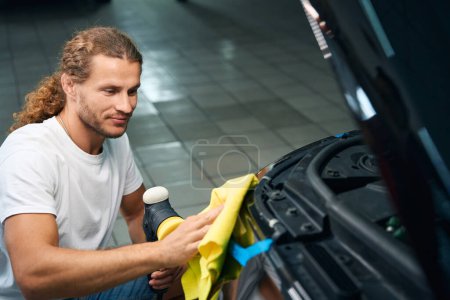 Foto de Mechanic in a car repair shop polishes the headlights of a car, he uses a soft yellow rag - Imagen libre de derechos