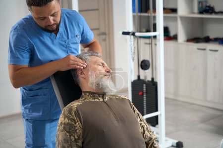 Photo for Chiropractor works with a patient in a rehabilitation center, he gives him a massage - Royalty Free Image