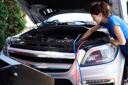 Téléchargez les photos : Mécanicien automobile utilise un équipement spécial pour remplir un climatiseur de voiture, une femme dans un uniforme bleu - en image libre de droit