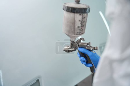 Photo for Professional paint injection tank is in the hands of a master, a man is working in protective equipment - Royalty Free Image