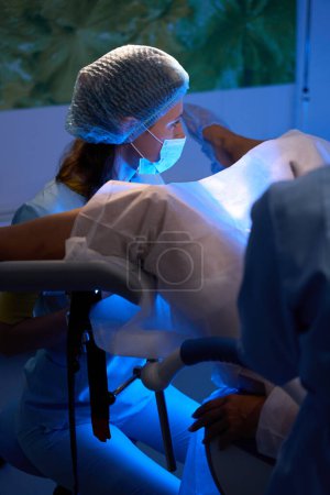 Téléchargez les photos : Médecin pratiquant le transfert d'embryons pour une patiente partielle sur un canapé médical dans une clinique de reproduction. Embryologie et biotechnologie - en image libre de droit