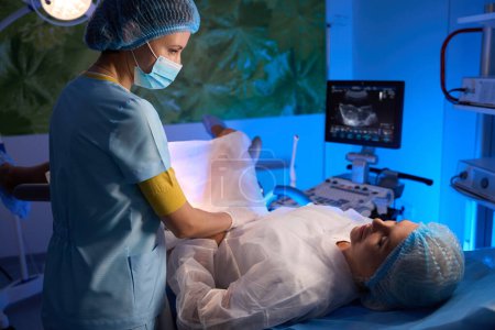 Foto de Doctora examinando a una paciente con equipo de ultrasonido en clínica reproductiva. Concepto de embarazo y maternidad - Imagen libre de derechos