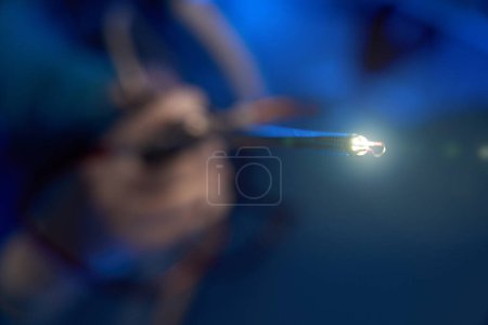 Téléchargez les photos : Gros plan de l'hystéroscope lumineux dans les mains d'un médecin masculin flou à la clinique. Concept de soins de santé - en image libre de droit