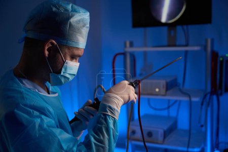 Foto de Vista lateral recortada del médico varón europeo preparando histeroscopio para cirugía en la clínica. Concepto sanitario - Imagen libre de derechos