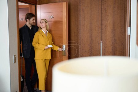 Foto de Hombre y mujer sonrientes entrando en la habitación del hotel mientras se miran - Imagen libre de derechos