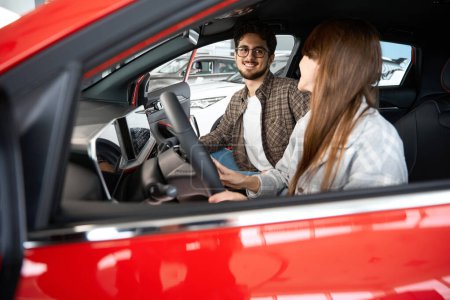 Foto de Hombre feliz y disfrutando al elegir y comprar un coche nuevo en el vehículo de prueba de sala de exposición en la concesionaria - Imagen libre de derechos