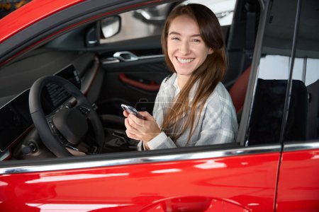 Foto de Mujer alegre sosteniendo llaves de mew automóvil vising concesionario para la compra de coches - Imagen libre de derechos