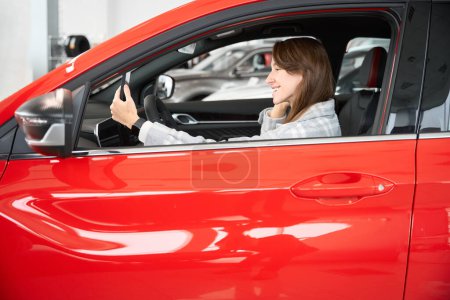 Téléchargez les photos : Jeune femme assise dans la voiture avec la diffusion de téléphonie mobile en direct vantant nouvelle automobile aux abonnés - en image libre de droit
