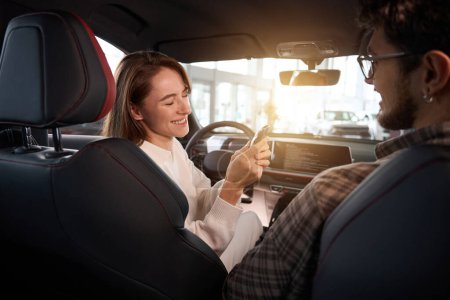 Téléchargez les photos : Joyeuse femme et homme achetant une nouvelle voiture tenant les clés souriant joyeusement - en image libre de droit