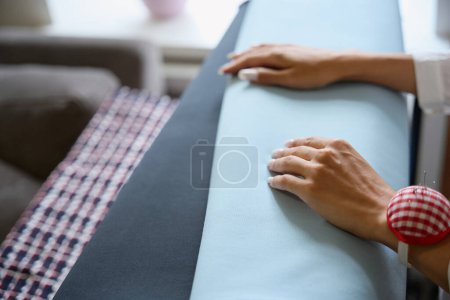 Photo for Craftswoman in a workshop chooses fabric for work, she has a needle bed on her hand - Royalty Free Image