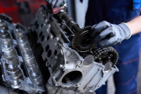 Foto de Reparando el motor de un coche moderno, un mecánico automático trabaja usando guantes de protección - Imagen libre de derechos