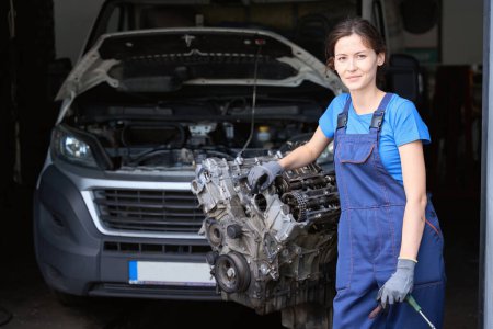 Téléchargez les photos : Mécanicien automobile sur le lieu de travail dans un atelier près de la voiture et du moteur - en image libre de droit