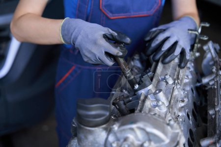 Téléchargez les photos : Femme mécanicien automobile sur le lieu de travail utilise un outil spécial, elle remplace les injecteurs - en image libre de droit