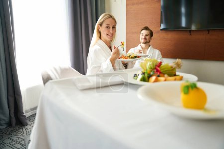 Photo for Married couple is having breakfast in their room in the recreation area, breakfast is served on a mobile table - Royalty Free Image