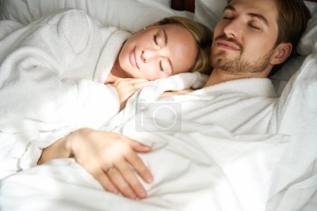 Téléchargez les photos : Jeune femelle somnolant sur mans épaule, couple reposant sur grand lit - en image libre de droit