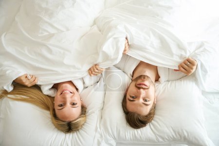 Foto de Guy y su novia están tumbados bajo una manta suave, están usando batas de terry de hotel - Imagen libre de derechos
