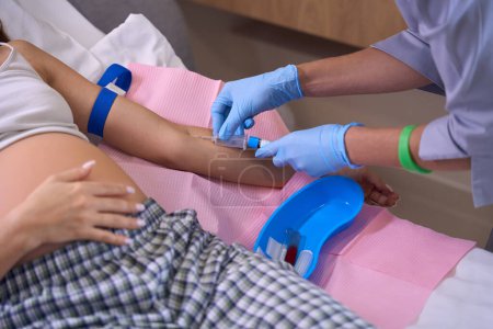 Téléchargez les photos : Image partielle d'une infirmière faisant une injection avec la seringue d'une femme enceinte sur un lit médical à l'hôpital. Concept de grossesse et de maternité - en image libre de droit