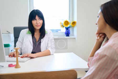 Photo for Adult european female gynecologist typing on computer while examining young caucasian pregnant woman in clinic. Concept of pregnancy examination - Royalty Free Image