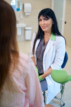 Téléchargez les photos : Gynécologue européenne souriante regardant une femme cultivée lors de son examen en clinique. Concept d'examen de grossesse - en image libre de droit