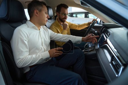 Foto de Cliente con un gerente en el interior de un coche moderno, el comprador estudia la funcionalidad de un modelo popular - Imagen libre de derechos