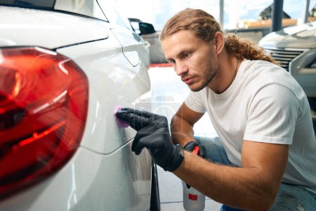Photo for Young master uses special clay in car detailing, a guy works with headlights - Royalty Free Image