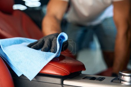 Foto de Maestro en guantes protectores limpia un reposabrazos de cuero, utiliza una servilleta azul - Imagen libre de derechos