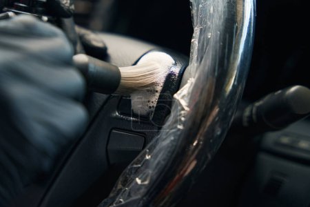 Photo for Man in protective gloves carries out detailing in the car interior, for cleaning he uses a special cleaning foam - Royalty Free Image