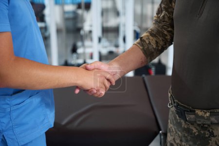 Photo for Medic greets a military man at a rehabilitation center, the man has scars on his arm - Royalty Free Image