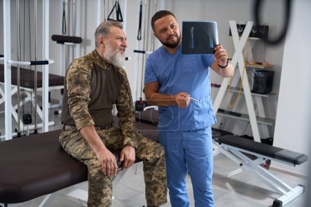Téléchargez les photos : Hommes barbus dans la salle de gym regardant les rayons X, équipement moderne à l'intérieur - en image libre de droit