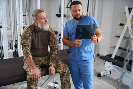 Foto de Dos hombres barbudos en el gimnasio mirando rayos X, equipo moderno en la habitación - Imagen libre de derechos